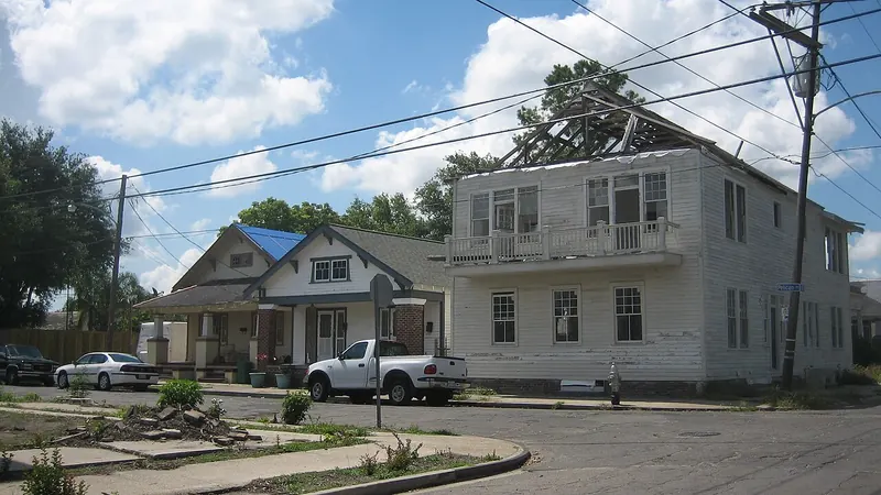 House with a blue tarp over its roof after a storm