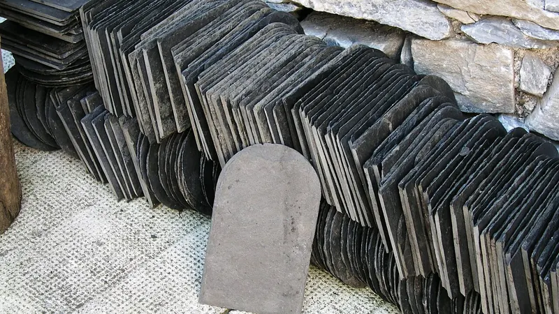 Stack of roofing slates with one slate standing upright
